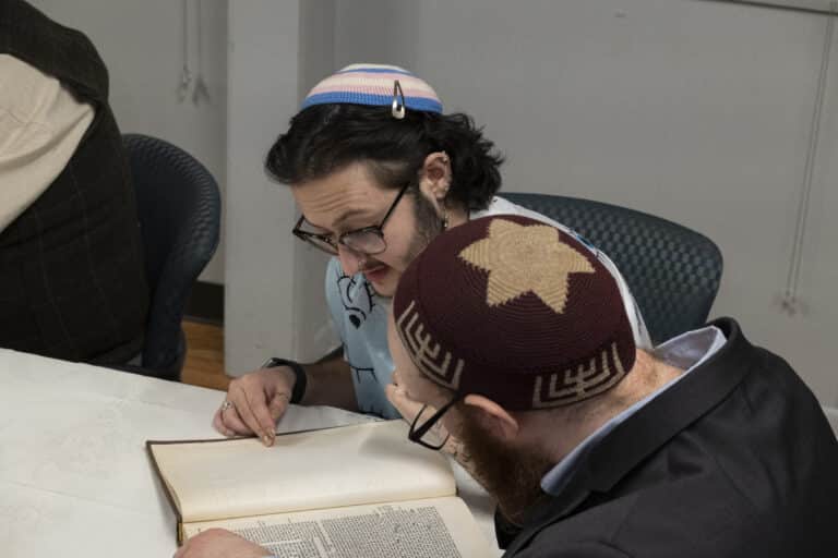 Rabbi Rank (R) and rabbinical student Ezra Kiers reading a book together.